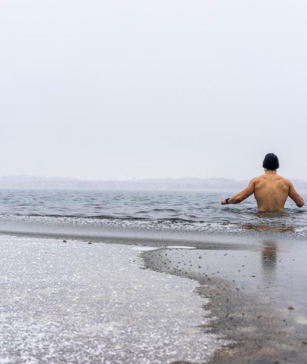 Fit man goes ice swimming into a lake